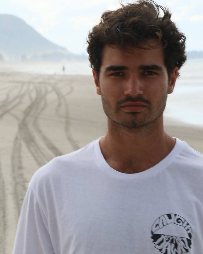 White t-shirt with the Caught by the Dawn logo on the beach