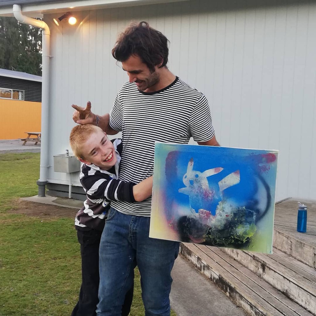 Facilitator and child celebrating with a Pikachu painting outdoors