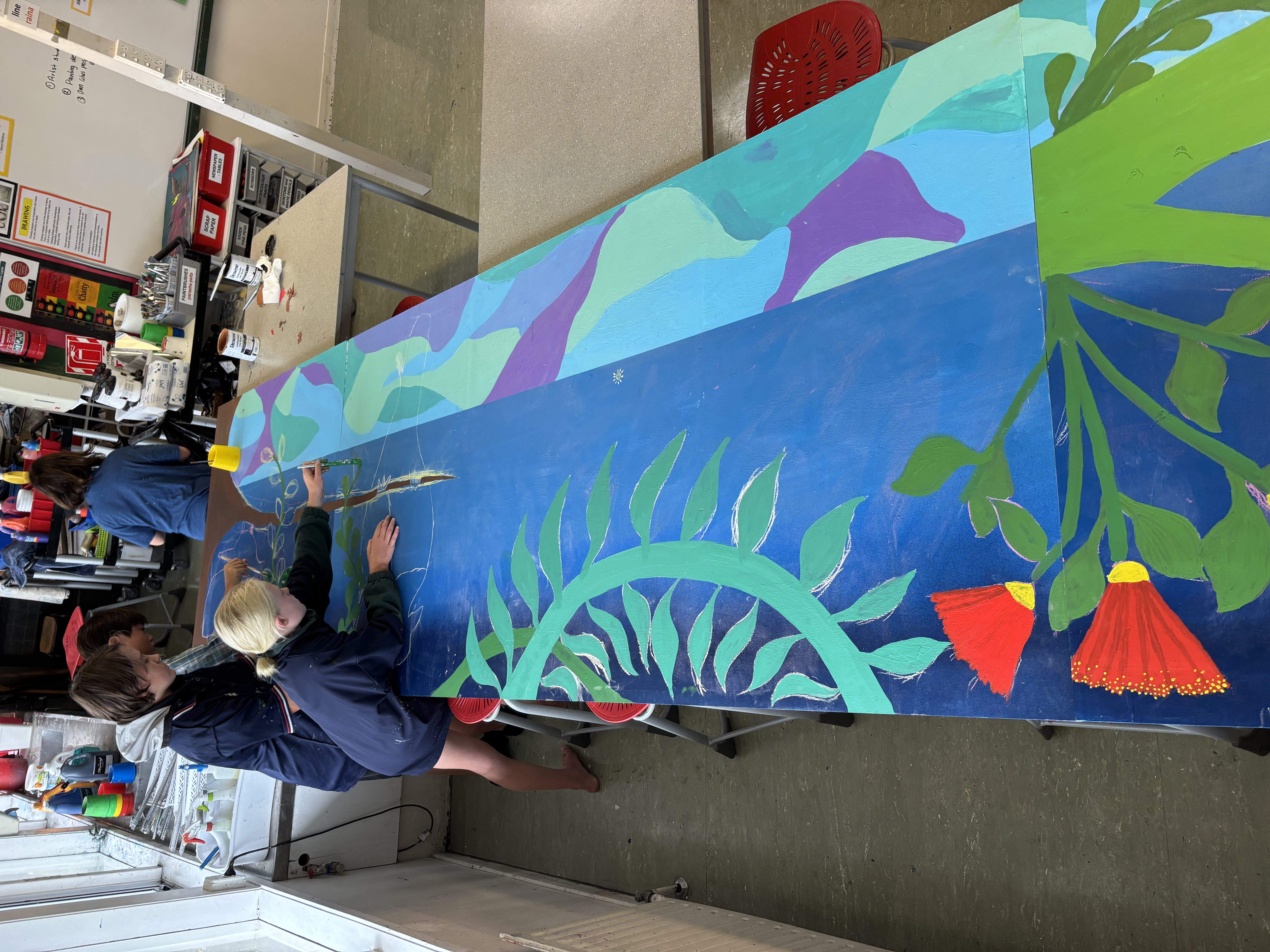 Students adding detail to a school mural painting